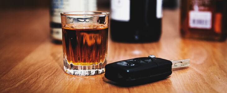 Close-up picture of car keys and whiskey on a bar counter