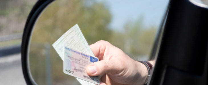 A man shows driver's license and vehicle registration at a check