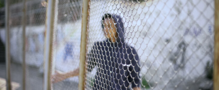 Afro-american boy behind fence, migrant child separated from family, detained