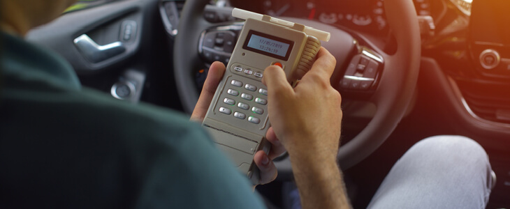 police officer in his patrol car, holding a breathalyzer test