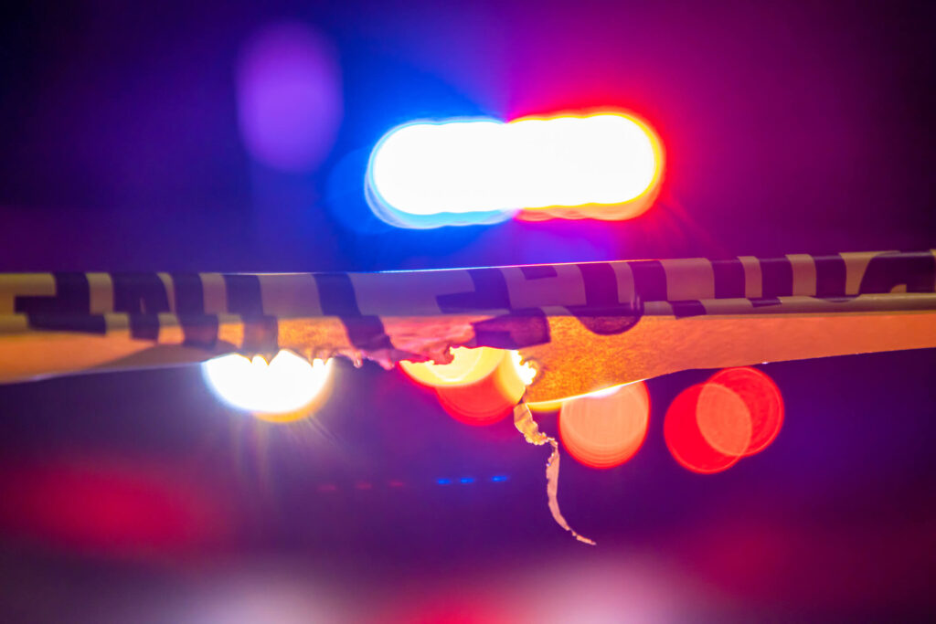 Police crime scene tape and emergency lights at night