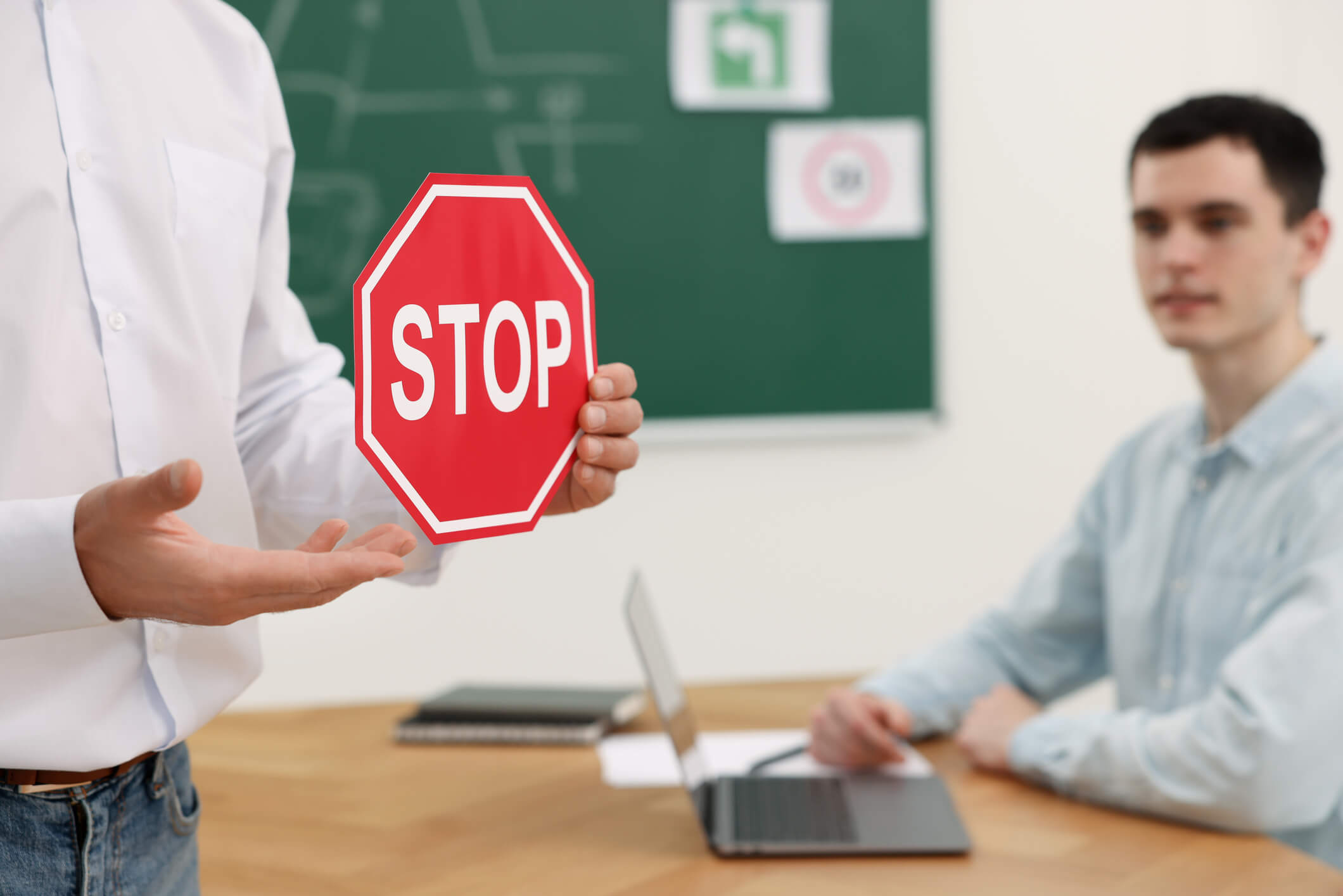 Teacher showing Stop road sign during lesson in driving school, closeup