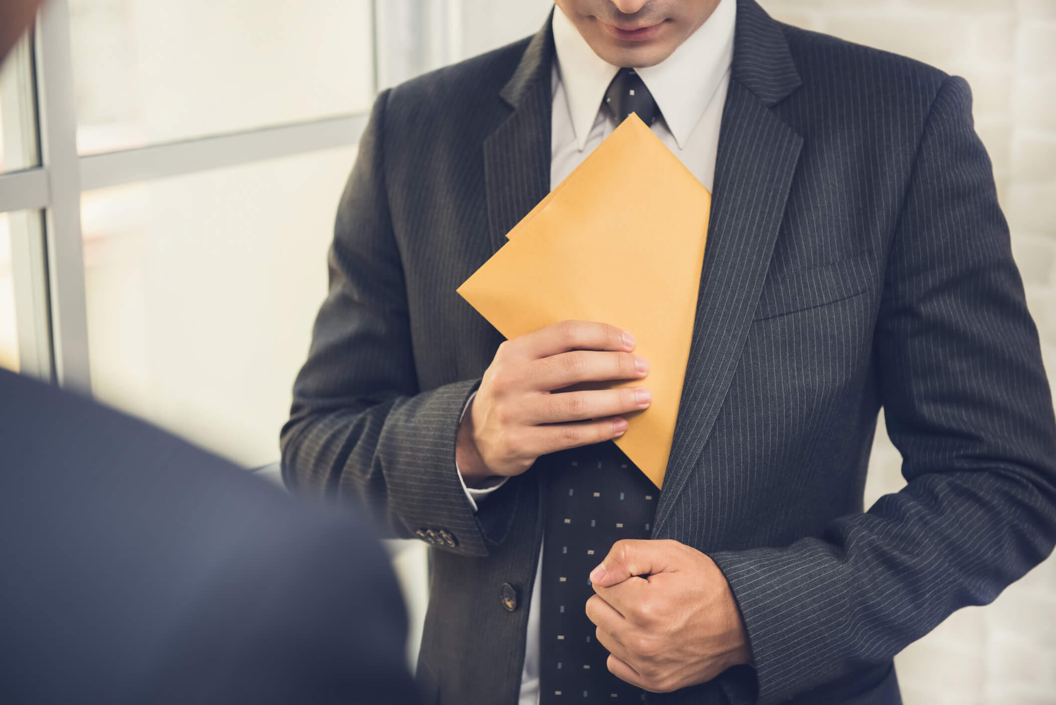 Businessman putting the envelope into his suit pocket - corruption and embezzlement concepts