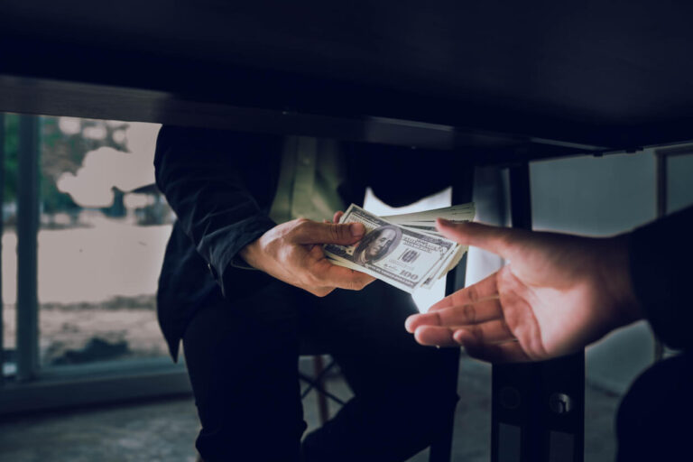 man taking bribe money under the table