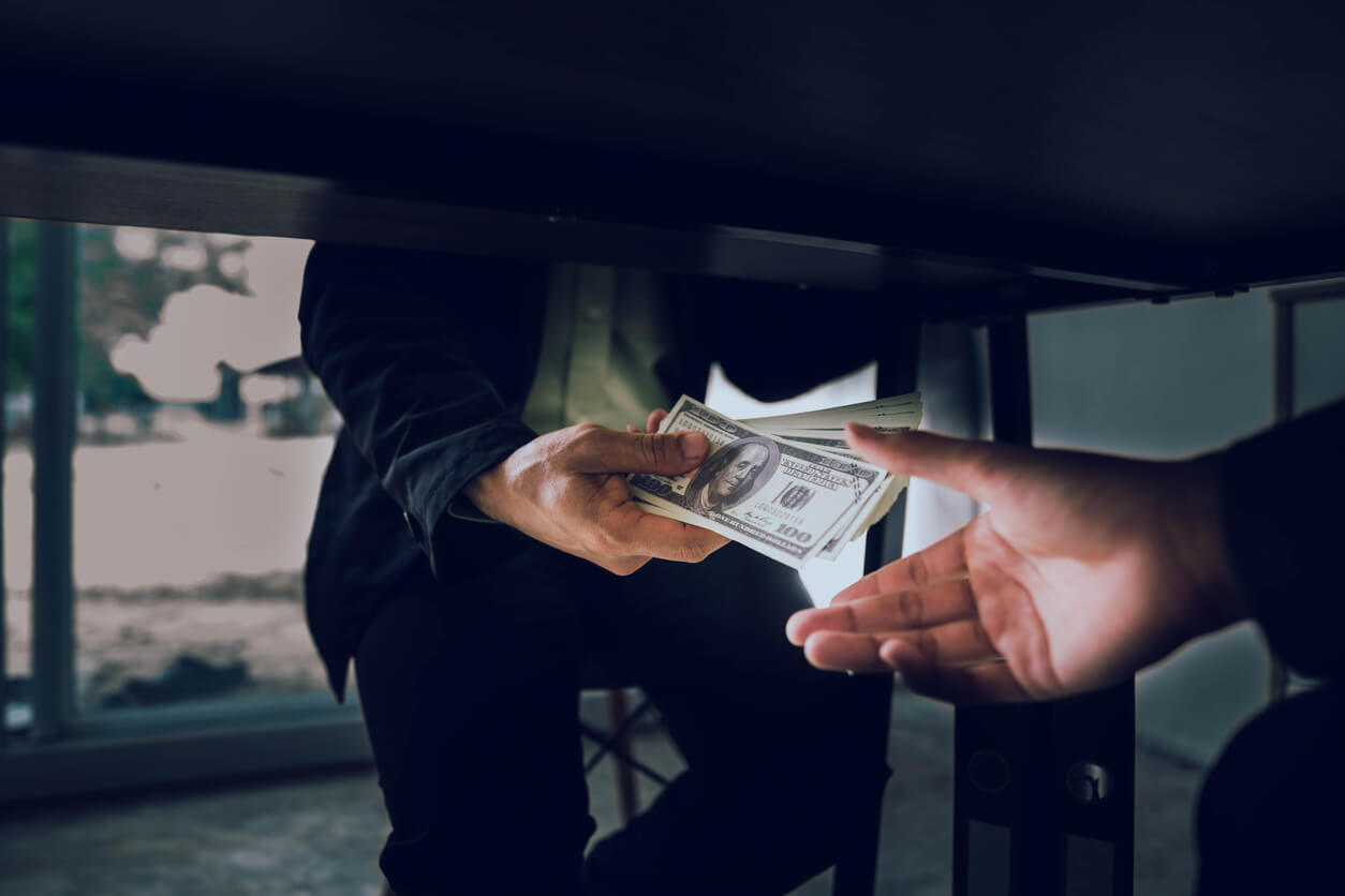 man taking bribe money under the table